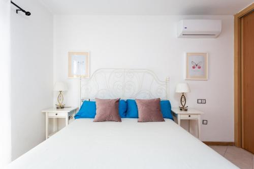 帕莱索海滩EDEN RENTALS Duplex Adeje Palace的卧室内的白色床和蓝色枕头