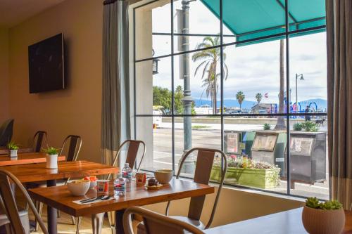 圣巴巴拉Beachside Inn的餐厅设有桌椅和大窗户。