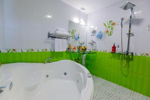 河内A25 Hotel - 45 Phan Chu Trinh的浴室铺有绿色瓷砖,配有浴缸。