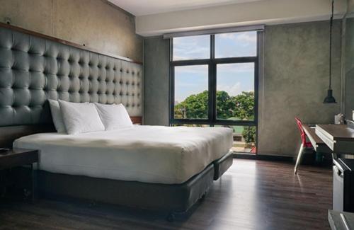 马尼拉The B Hotel Quezon City的一间卧室设有一张大床和一个大窗户