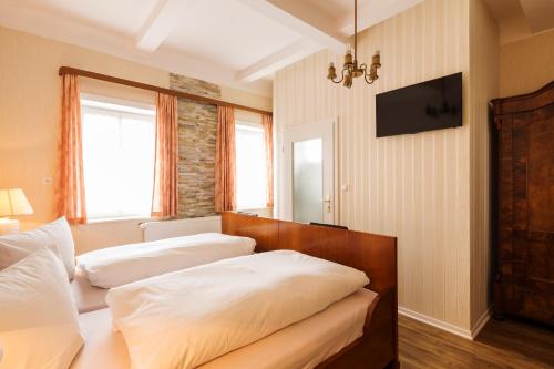 兰河畔马尔堡Hotel Haus Müller的一间卧室设有两张床,墙上配有电视。
