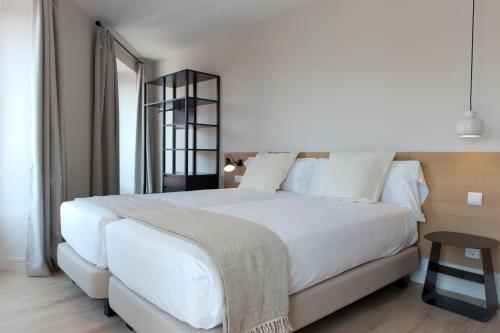 马德里马德里市中心MH公寓式酒店的卧室配有一张白色的大床和一张桌子