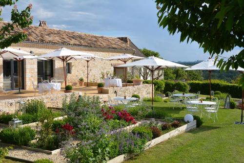 圣耐克森La Chartreuse du Bignac - Teritoria的一座花园,在一座建筑前设有桌子和遮阳伞