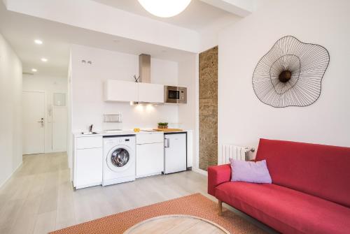 圣地亚哥－德孔波斯特拉Santiago Center Rooms的一间带红色沙发的客厅和一间厨房