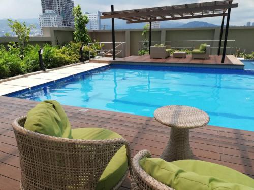 宿务Nica's Place Property Management Services at Horizons 101 Condominium的一座带椅子和桌子的游泳池位于大楼旁