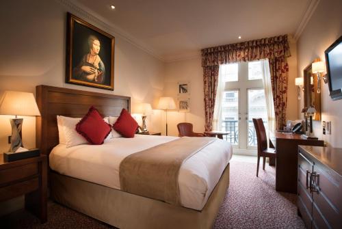 伦敦The Royal Horseguards Hotel, London的配有一张床、一张书桌和一扇窗户的酒店客房