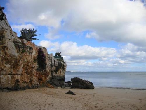 卡斯卡伊斯套房住宿加早餐旅馆的一个带岩石墙的海滩和大海