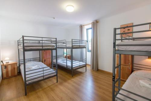 蓬塔德尔加达Change The World Hostels - Açores - Ponta Delgada的铺有木地板的客房内配有三张双层床。