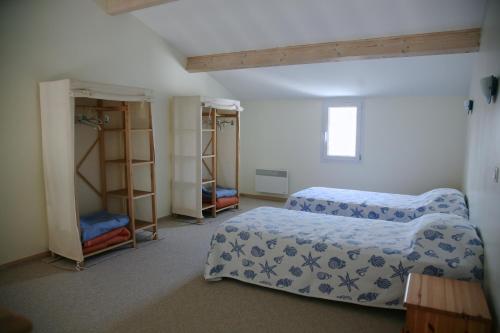 Grand-Village-PlageHotel Residence Les Alizes的一间卧室配有两张床和书架。