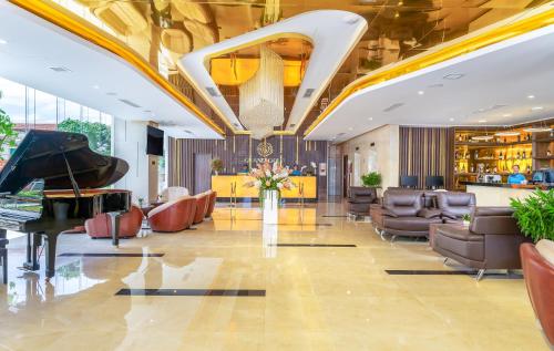 岘港格兰德戈尔德酒店的大堂设有三角钢琴和椅子