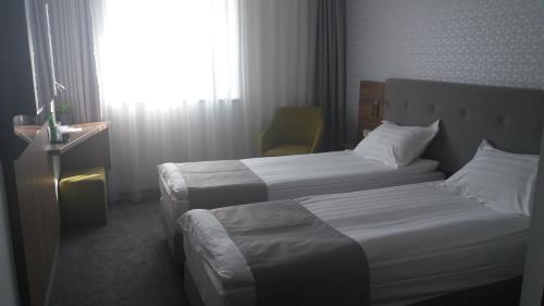 罗兹Abton Hotel的酒店客房设有两张床和窗户。