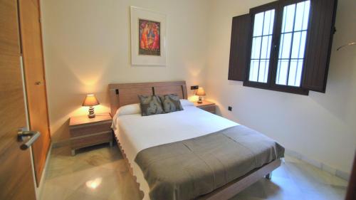 塞维利亚圣洛伦佐塞维利亚生活公寓酒店的一间卧室配有带2个床头柜和2个窗户的床