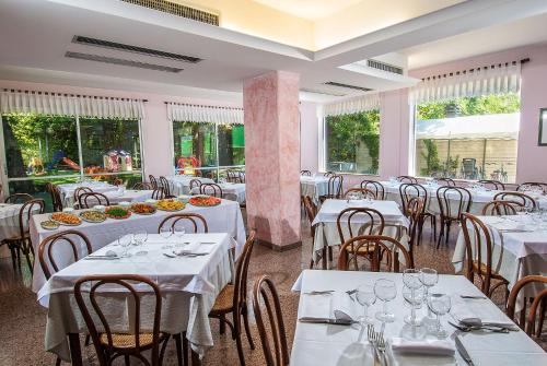 西尼加利亚利昆尔齐酒店的餐厅设有白色的桌椅和窗户。