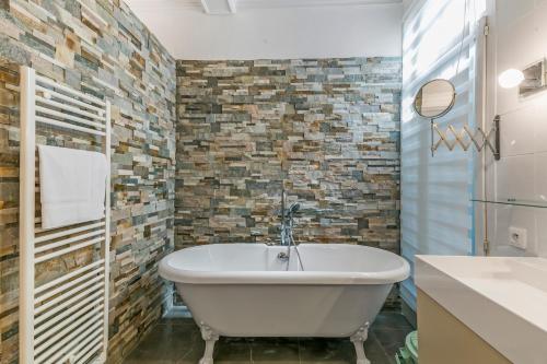 蒙彼利埃Villa jeu de paume - Première conciergerie的一间带白色浴缸和砖墙的浴室