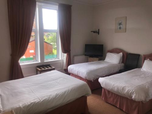 邓弗里斯Aberdour Guest House的酒店客房设有两张床和窗户。