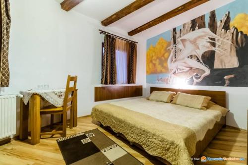 DrăguşPensiunea Casa Zmeilor的卧室配有一张床,墙上挂有绘画作品