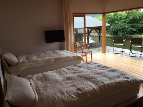 京丹后市Waterside Cottage Heron的一间带两张床的卧室和一个带电视的阳台