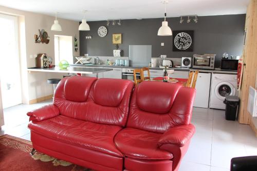 Aucey-la-PlaineCute Gite family Aucey Mont Saint Michel的客厅里设有一张红色的真皮沙发,还有一间厨房