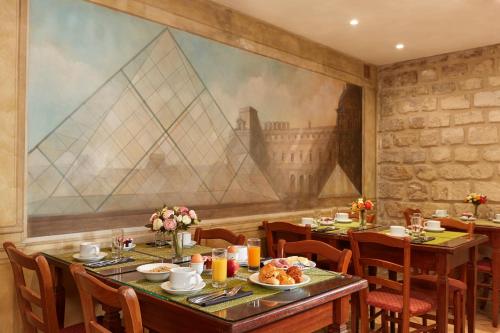 巴黎巴那斯峰达格尔酒店的一间带桌椅的用餐室和一幅大画