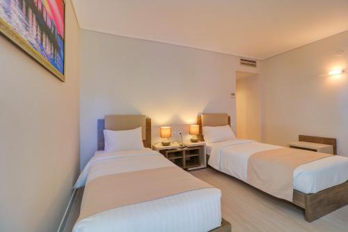 雅典Palace Hotel Glyfada的配有2盏灯的酒店客房的2张床