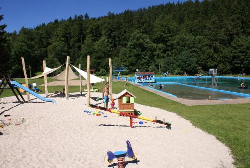 鲁拉Ferienhaus Lichtung的一个带滑梯和游泳池的游乐场的公园