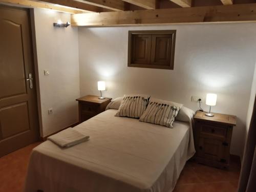 洛萨尔德拉韦拉Hostal El Rincon de la Vera的一间卧室配有一张带2个床头柜和2盏灯的床。