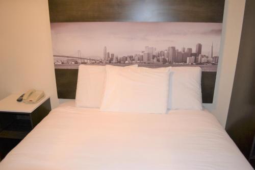 旧金山福尔瑟姆旅馆的城市天际线客房的一张带白色枕头的床