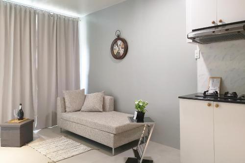 麦克坦GM Rentals SafeStay Apartment at Mactan Airport的客厅配有椅子和墙上的时钟