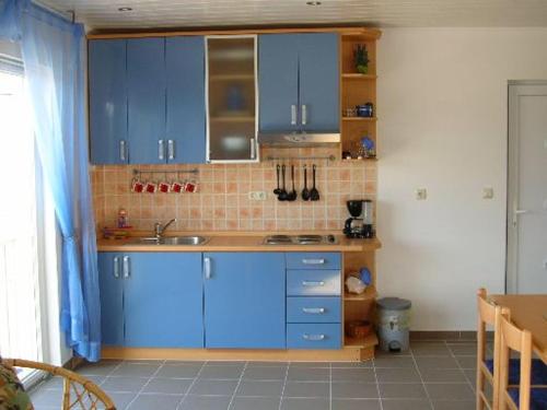 坎普尔Waldeck Apartment 1的厨房配有蓝色橱柜和瓷砖墙