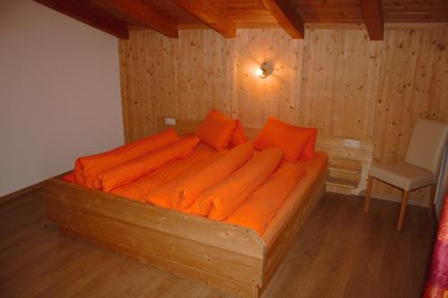 朗根费尔德阿尼塔公寓酒店的客房内的一张带橙色床单的木床