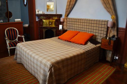 巴黎Hotel Windsor Home的一间卧室配有一张带橙色枕头的床和壁炉