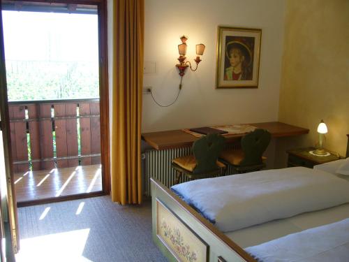 阿皮亚诺苏拉斯特拉达Hotel Gasthof WASTL的一间卧室配有一张床、一张桌子和一个窗户。