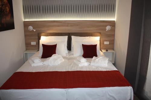 罗维尼AURA Residence的一间卧室配有一张带红色和白色枕头的大床