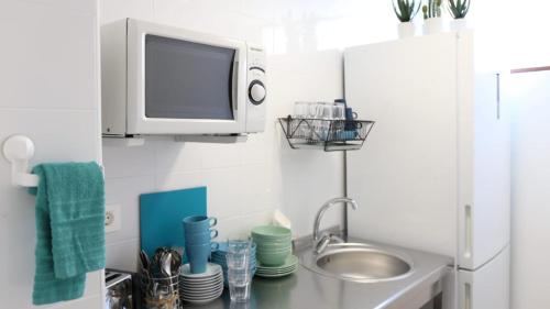 阿雷西费Hostal Residencia Cardona的一个带水槽的厨房和墙上的电视