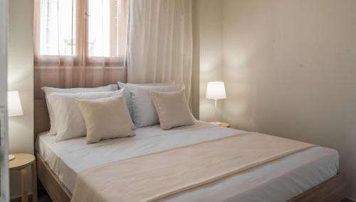 干尼亚Aelia Apartments的白色的床、白色枕头和窗户