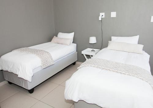 温特和克RnB's Studio Apartment的配有2张床铺、白色床单和桌子的客房