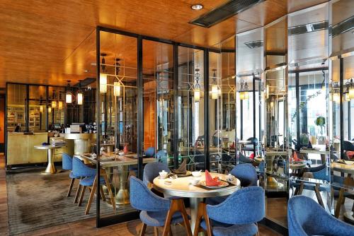 广州广州岭南五号酒店的餐厅设有蓝色的椅子和桌子以及窗户。