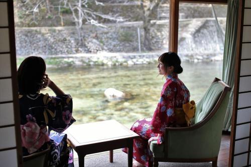 镜野OkutsuHotSpa IkedayaKajikaen的两个和服女装坐在窗边