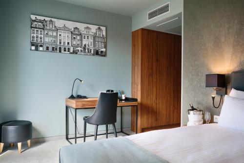 波兹南Focus Hotel Poznań的一间卧室配有一张桌子、一张床和一张带椅子的桌子。