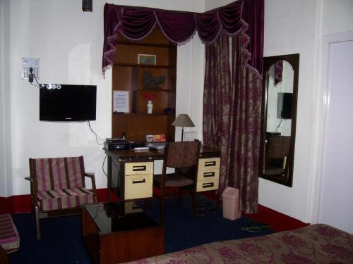加尔各答蓝筹旅馆的一间卧室配有书桌和一张带电脑的床。