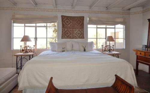 圣米格尔-德阿连德圣多明哥套房公寓式酒店的卧室配有一张白色大床和两个窗户