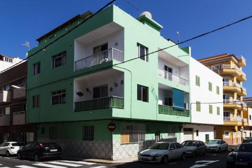 拉斯加莱塔斯Typical Canarian apartment的一座绿色和白色的建筑,前面有汽车停放