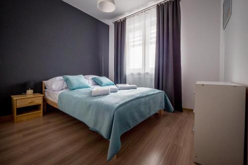 乔左维尔考普尔斯基FUDA APARTAMENT BRUKSELSKA 11的一间卧室配有一张带蓝色床单的床和一扇窗户。