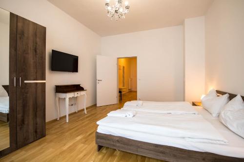 格拉茨Minihotel Graz Apartments的一间卧室配有两张床、一张桌子和一台电视。