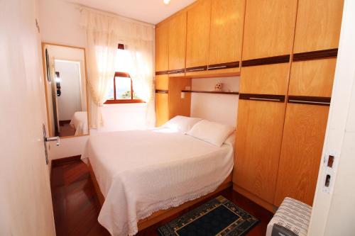 坎波斯杜若尔当Apartamento Vista para as Montanhas的一间小卧室,配有一张白色的床和木制橱柜