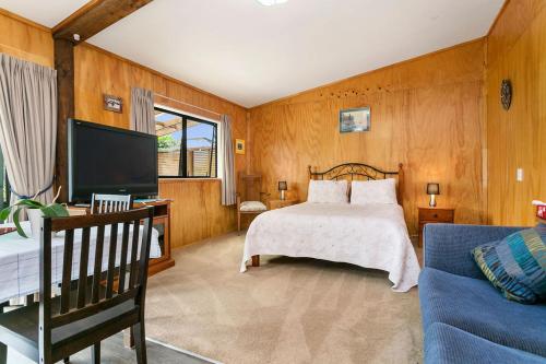 TamaherePickering Barn Stay的一间卧室配有一张床、一台电视和一张沙发