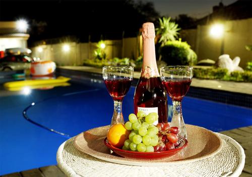 约翰内斯堡Rekky Signature Guesthouse的一张桌子,上面放着两杯葡萄酒和一碗水果