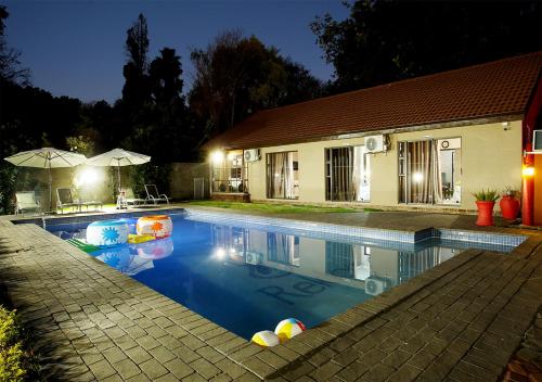 约翰内斯堡Rekky Signature Guesthouse的夜间在房子前面的游泳池