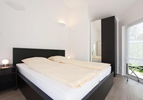 Hörselberg-HainichFerienhäuser am Hainich的一间卧室配有一张白色大床和黑色床头板