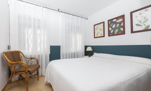 滨海托萨Apartments Mar de Tossa的一间卧室配有一张大床和一把椅子